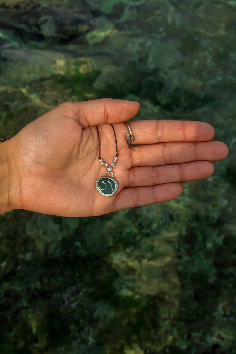 Colgante elaborado con alpaca en forma de ola con fondo de agua