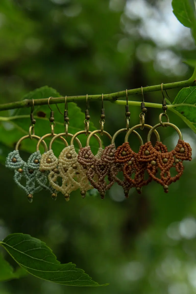 Pendientes artesanales de macramé de color verde menta, mantequilla, beige y naranja en una rama
