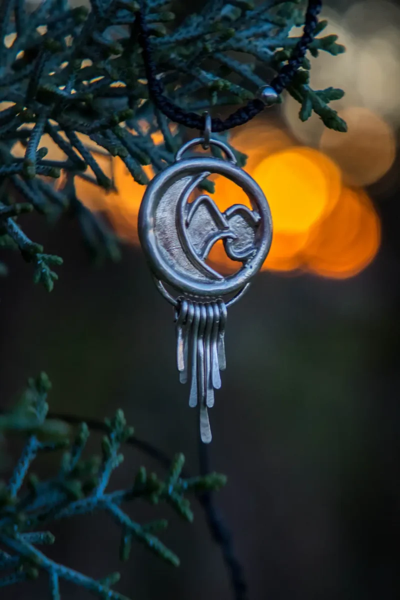 Colgante artesanal elaborado con alpaca con forma de mar y montaña